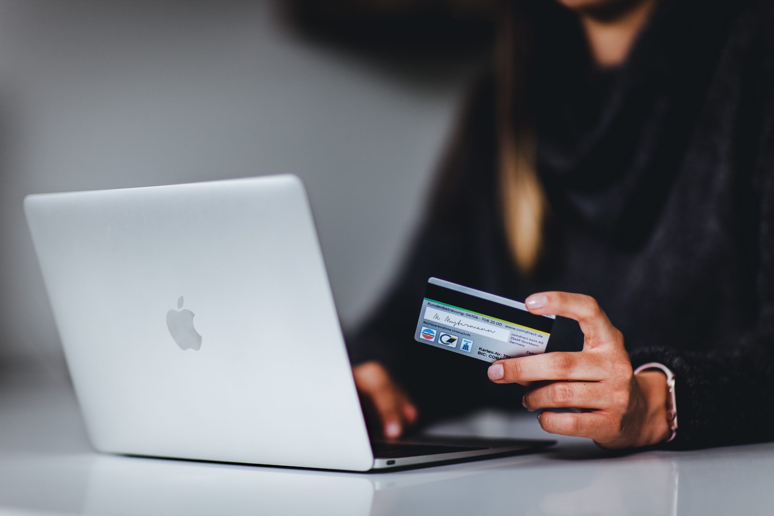 pessoa com cartão de crédito nas mãos e laptop efetuando uma compra online
